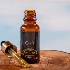Krople propolisu na drewnianej desce. Dowiedz się, jak stosować propolis na jelita, by wesprzeć swoje zdrowie.