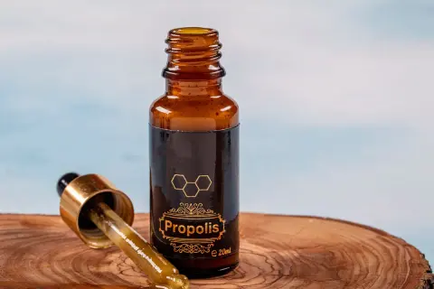 Krople propolisu na drewnianej desce. Dowiedz się, jak stosować propolis na jelita, by wesprzeć swoje zdrowie.