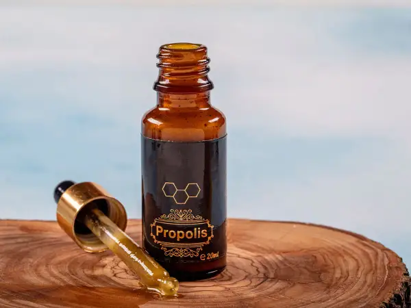 Krople propolisu na drewnianej desce. Dowiedz się, jak stosować propolis na jelita, by wesprzeć swoje zdrowie.
